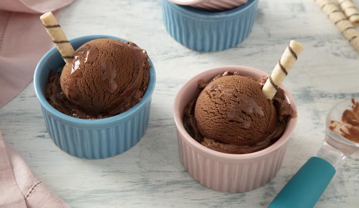 Foto da receita de MOÇA Sorvete com Nescau. Observa-se dois potinhos individuais, um rosa e um azul, um com cada bola de sorvete. Cada potinho tem um palito de wafer.