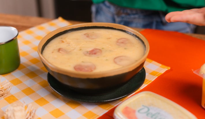 Caldo cremoso de macaxeira com rodelas de linguiça calabresa e cheiro-verde