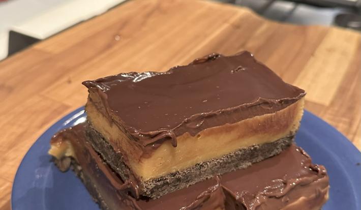 Fotografia de três porções da torta escocesa em um prato de vidro azul raso sobre a tábua de madeira.