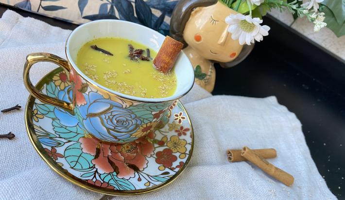 Imagem da receita de GoldenMilk – Bebida Dourada em cima de uma toalha branca e ao lado canelas em pau