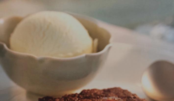 Foto da receita de Bolo Quente com Geleia da consumidora Caroline Lima. Observa-se um bolo baixo de chocolate com calda brilhosa por cima e, atrás, em um pote de cerâmica, uma bola de sorvete de creme.