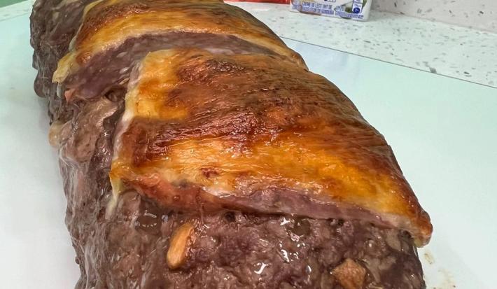 Foto da receita de rocambole de carne moída servida em uma porção grande sobre uma mesa branca