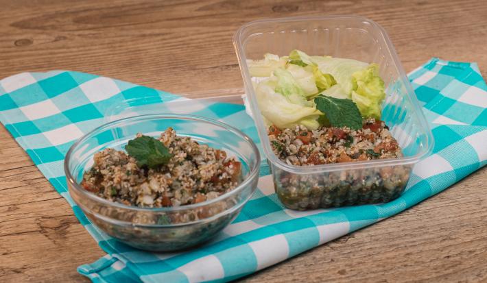 Foto de dois recipientes com a receita de Tabule dentro. Ambos estão sobre um tecido azul e branco quadriculado em uma bancada de madeira