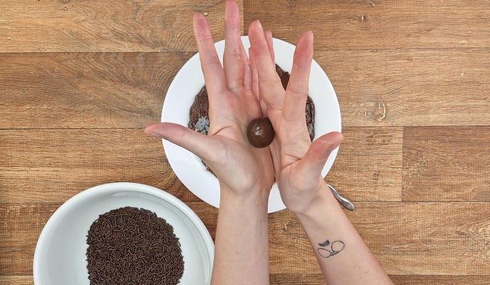 Mãos enrolando brigadeiros