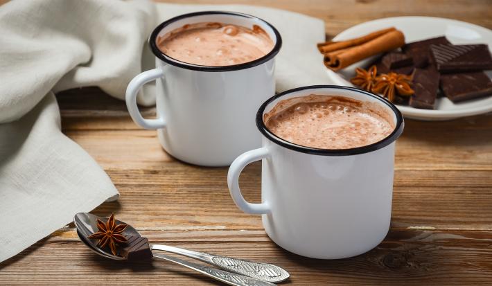 fotografia em tons de branco e marrom tirada de duas xicaras brancas com chocolate quente dentro