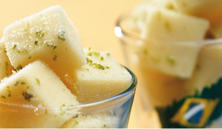 em dois copos transparentes contém cubos de gelatina com raspas de limão. No segundo copo ao fundo contém a foto da bandeira do Brasil.