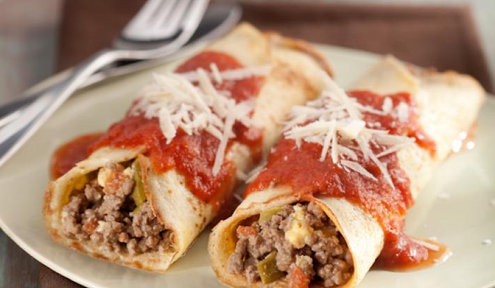 Foto de duas panquecas de carne moída cobertas com molho de tomate e queijo em um prato branco em cima de um pano marrom