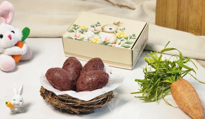 Foto da receita de Mini Ovinho de Páscoa com Ameixa e Mucilon Seleção da Natureza. Observa-se quatro ovinhos de páscoa dentro de uma cesta com decorações de Páscoa no entorno.