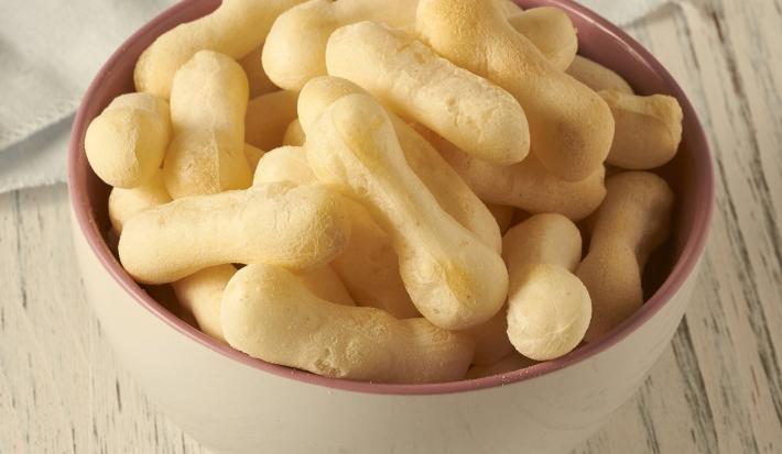 Imagem de um bowl branco com borda rosa com biscoitos de polvilho em formato de palito.