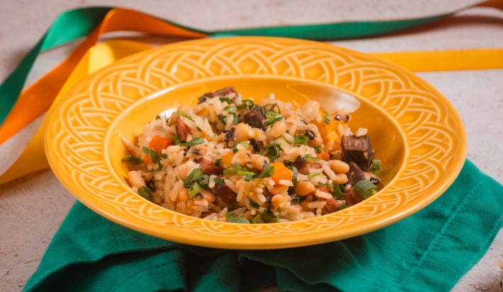 Baião de dois cremoso com carne seca, feijão-fradinho, queijo coalho e coentro