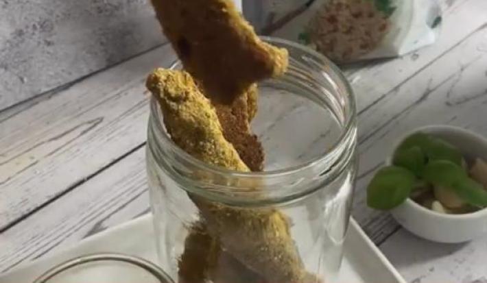 Foto em tons de cinza da receita de palitos saudáveis servidos dentro de um recipiente de vidro com tampa, sobre uma base de porcelana branca. Ao fundo uma embalagem de quinoa real grãos nature's heart