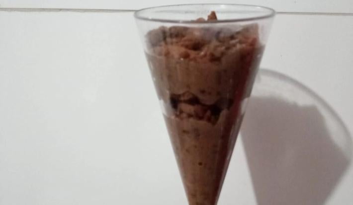 Fotografia com uma sobremesa de brigadeiro e biscoito bono chocolate triturado.