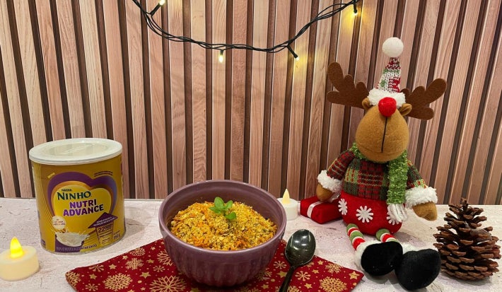 Fotografia em tons de vermelho com um pote roxo ao meio e a farofa de cenoura dentro.