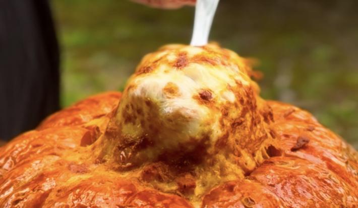 Fotografia de uma colher puxando o strogonoff de camarão com bastante queijo de dentro da abóbora moranga.