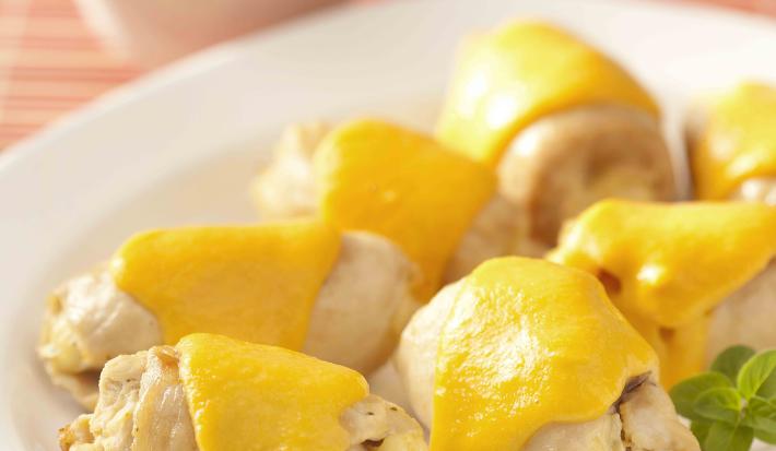 fotografia em tons de bege, branco e amarelo tirada de uma bancada bege. Contém um prato redondo branco com os Enroladinho de Frango.