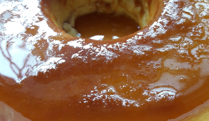 Foto em tons de bege claros e escuros da receita de pudim de pão com um furo central