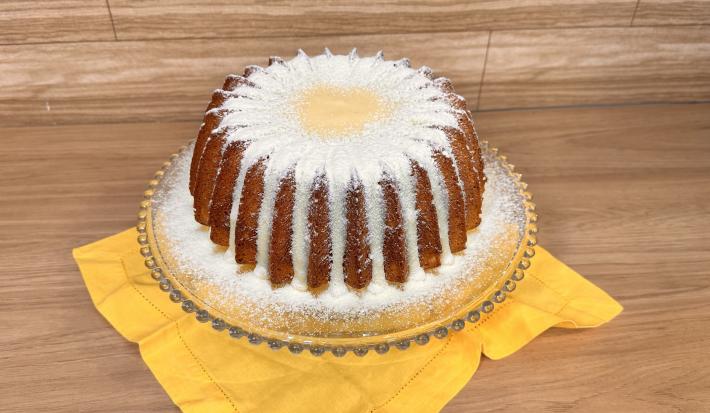 Fotografia em tons de amarelo com um prato de vidro ao centro. Em cima do prato existe um bolo em formato de estrela coberto com um brigadeiro de Leite NINHO e mais NINHO polvilhado