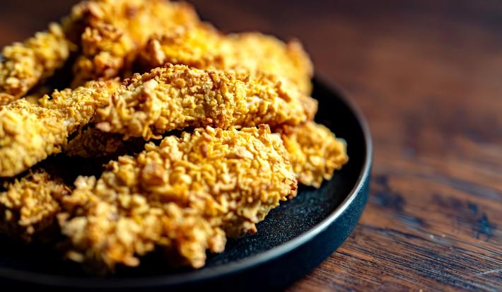 Fotografia de uns peitos de frango empanados e crocantes, parte de uma receita de sambiquira.