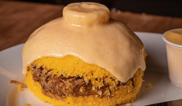Fotografia de cuscuz de carne seca com fatia de queijo em cima.