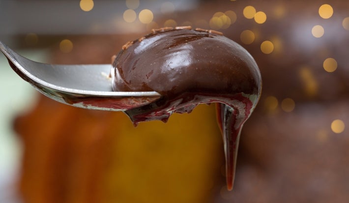 Fotografia de uma colher de sopa segurando um pouco do brigadeiro cremoso de chocolate.