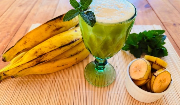 Fotografia em tons de verde e amarelo com um copo de shake ao centro. Em cima do copo,