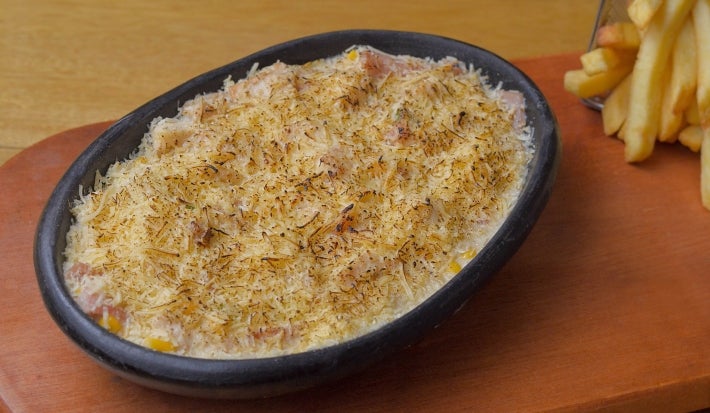Em uma refratário, porção de arroz com queijo gratinado.