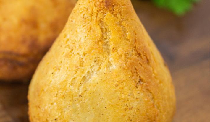 Fotografia de uma coxinha de jaca sobre uma tábua de madeira.