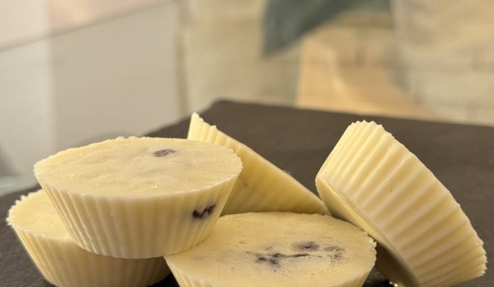 Fotografia em tons claros com uma fotografia de vários bombons brancos ao centro feitos em forminhas de silicone.