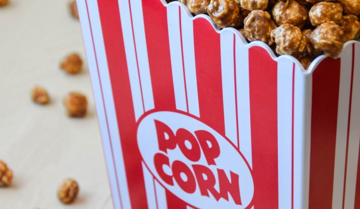 fotografia de um pacote de pipoca com listras vermelhas e brancas com pipocas carameladas dentro