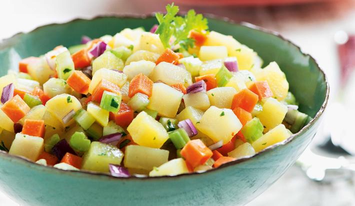 foto tirada de um suporte para servir pratos na cor verde e dentro contém a salada com pedaços de batata-doce, salsão, cenoura e cebola roxa.