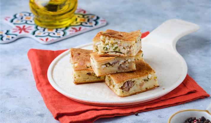 Fotografia mostra pedaços de torta de sardinha sobre um prato branco.