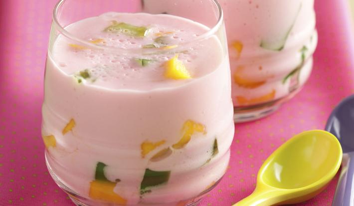 fotografia em tons de cinza e rosa de uma bancada cinza vista de frente, contém um pano rosa com dois copos transparentes e ambos contém a bebida com pedaços de frutas