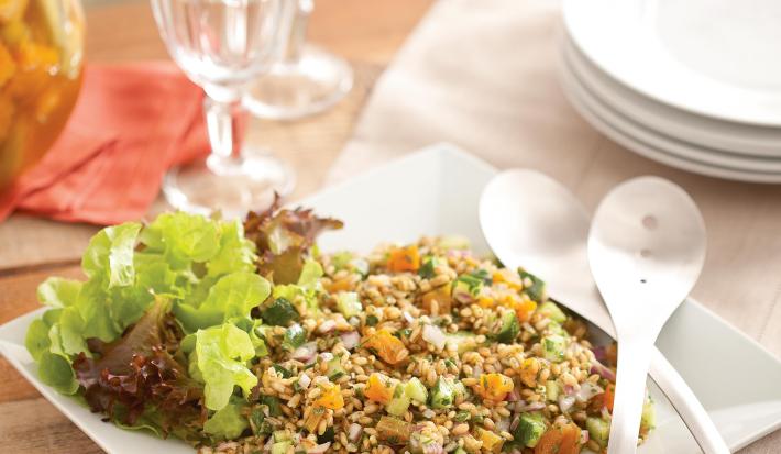 uma mesa contém duas taças de vidro, pratos e um prato quadrado com a salada de sevadinha e duas colheres ao lado.