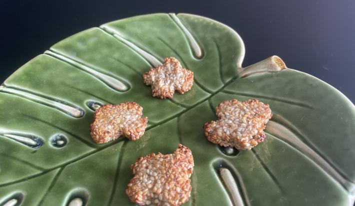 Imagem da receita de Biscoito de Banana e Gergelim em um recipiente de vidro em formato de folha verde