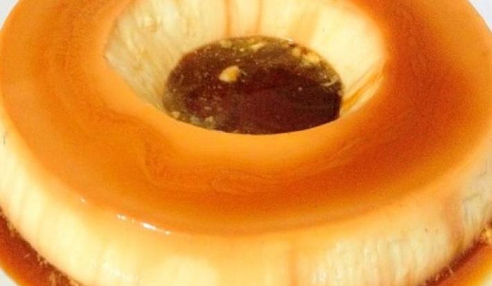 Foto em tons de caramelo da receita de pudim de leite em pó servida em uma porção inteira