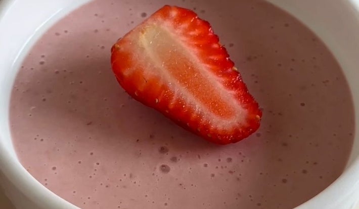 Fotografia de três ramekins brancos com mousse de morango e metade de um morango por cima, decorando cada um.