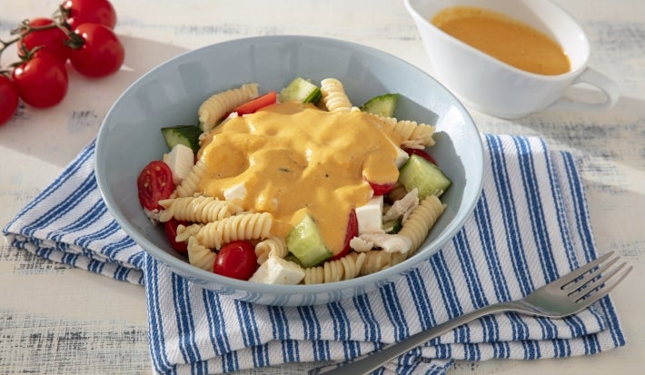 Fotografia mostra um prato azul com fusilli, cubos de vegetais, frango e tomates cereja, tudo envolvido em um molho amarelo cremoso, com cores vibrantes em destaque e textura suculenta. Fotografia mostra um prato azul com fusilli, cubos de vegetais, frango e tomates cereja, tudo envolvido em um molho amarelo cremoso, com cores vibrantes em destaque e textura suculenta.