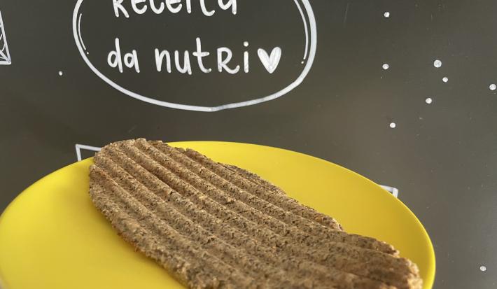 Imagem da receita de Pão de microondas sem glúten, em um prato amarelo e ao fundo uma lousa escrito em giz "Receita da nutri"