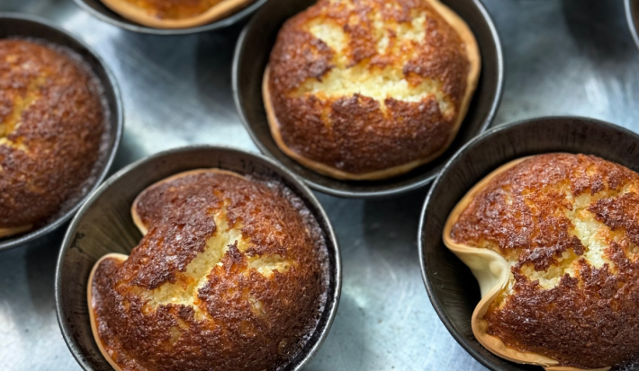Fotografia mostra as cocadas vistas de cima, dispostas em forminhas de alumínio. A massa de pastel forma cestinhas douradas com o recheio em textura de bolo.