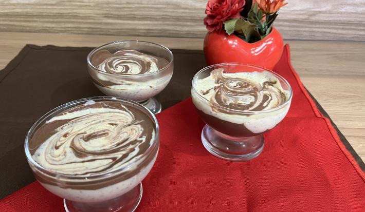 Fotografia de três recipientes com mousse de maracujá com creme de nescau mesclado. Os recipientes estão sobre um pano vermelho e um pano marrom de tom escuro.