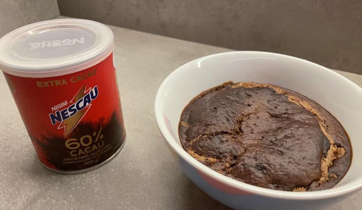 Receita de Baked Oats, em um recipiente branco, sobre uma mesa e ao lado o Nescau 60% Cacau