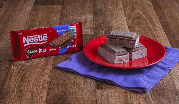 Fotografia de pedaços de palha italiana de chocolate cortadas em formato retangular sobre um prato vermelho.