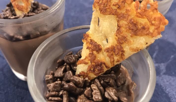 Foto aproximada de um brigadeiro no copinho, decorado com grão de café e um biscoito