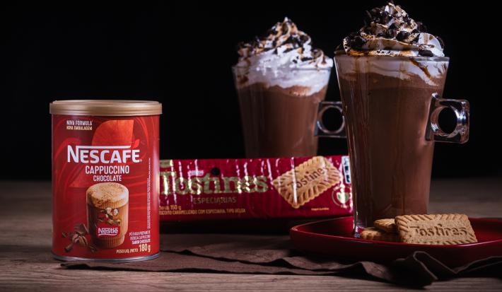 Foto da receita de cappuccino crocante servida em duas canecas altas de vidro sobre uma mesa de madeira