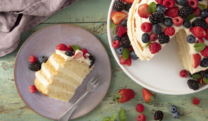 Imagem do bolo naked cake de morangos vista de cima, com destaque a um prato com uma fatia do bolo.