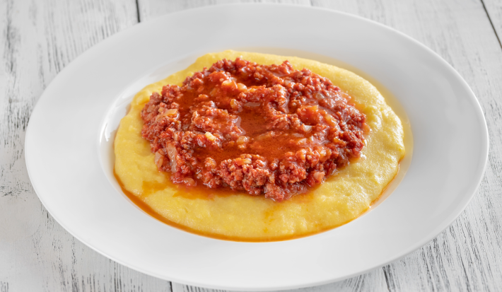 Fotografia mostra um  angu cremoso, coberta com carne moída