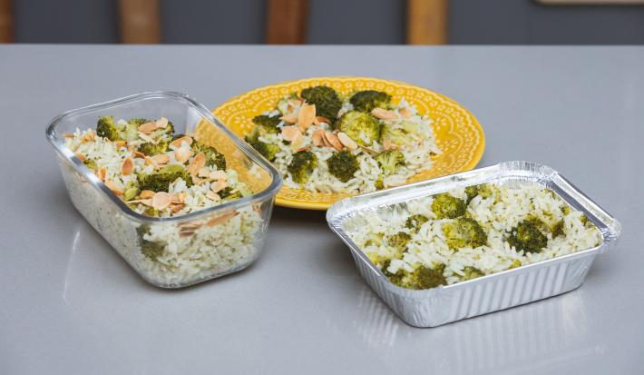 Foto da receita de Arroz com Brócolis em uma vasilha de vidro, uma forma de alumínio e sobre um prato amarelo, em cima de uma bancada