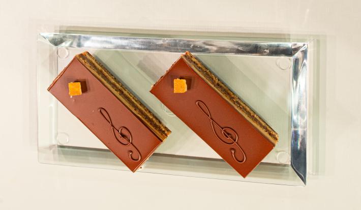 Foto vista de cima da receita de bolo ópera, lindíssimo, decorado com o desenho de uma clave musical feita com chocolate