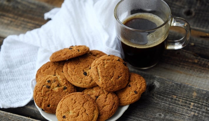Em cima de uma mesa, prato com biscoitos em redondos crocantes e dourados.