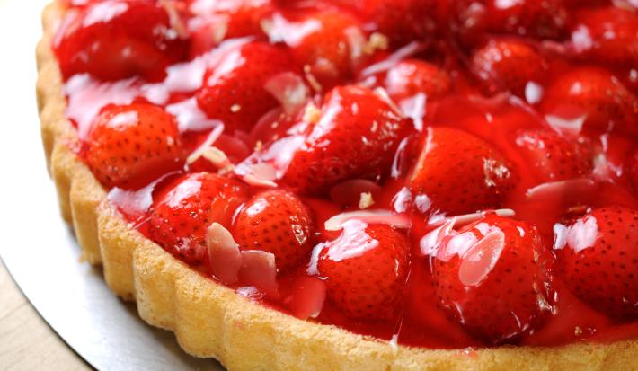 Fotografia de uma torta de morango com massa com Cereal NESTON e uma calda brilhosa por cima. A torta está sobre um fundo falso da forma.